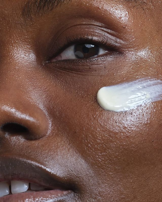 Close-up of a person's face with a skincare product applied to the cheek.